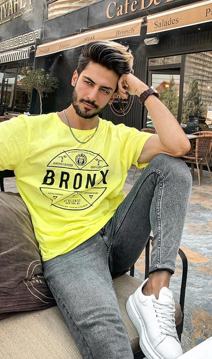 full length of man in yellow t-shirt and beige pants sitting with crossed  legs on grey background,stock image Stock Photo - Alamy