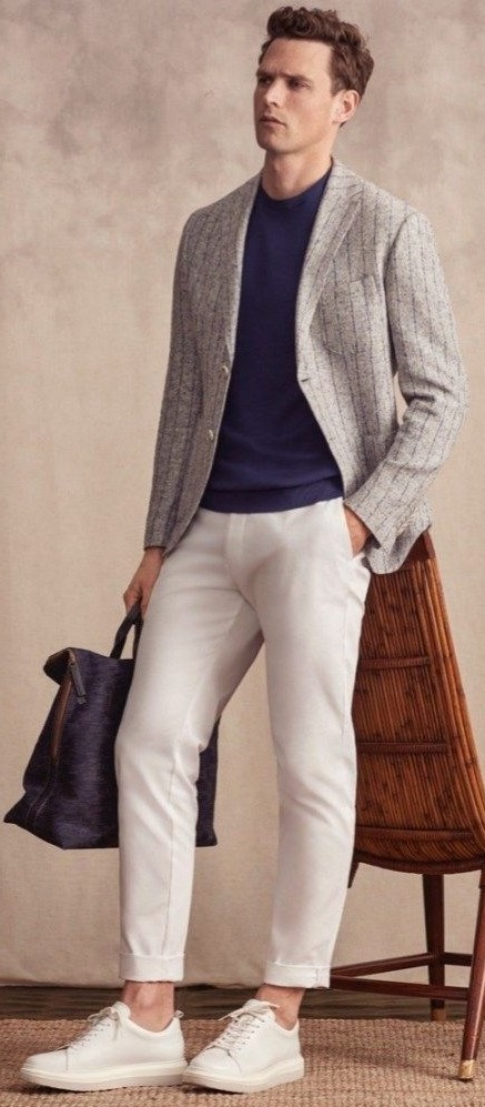 Grey suit with navy blue t-shirt and cream chinos and white shoes, holding a bag_