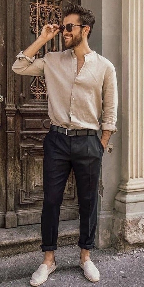 beige shirt with black trousers wearing a leather boot accessorized with shades_