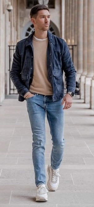 beige t-shirt with blue denims and dark blue jacket wearing white sneakers_