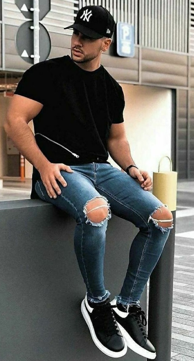 black t-shirt with ripped denims and a cap wearing black shoes_