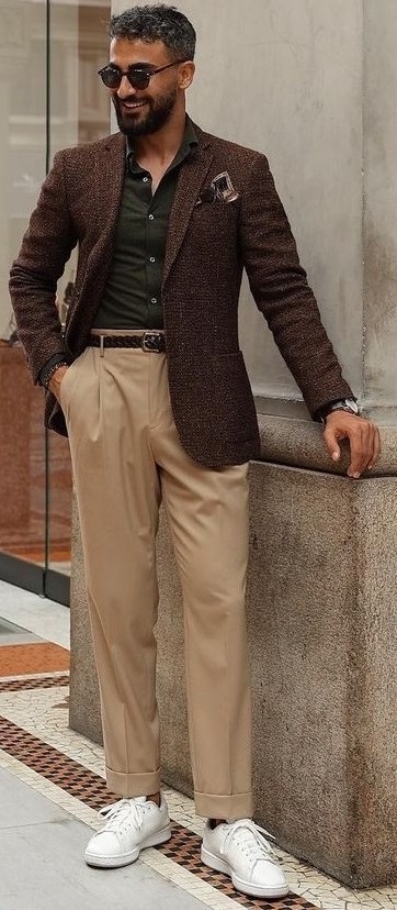 green undershirt with beige trousers and brown leather jacket, wearing shades and white sneakers_