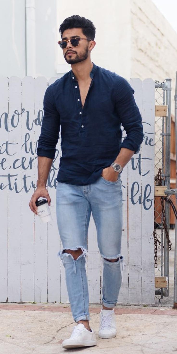ripped denims with blue half buttoned t-shirt, rolled up sleeves accessorized with watch and shades and white sneakers_