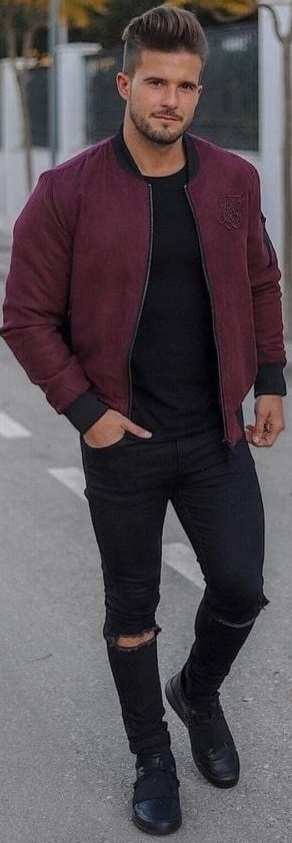 maroon bomber jacket with black shirt and black ripped denims, with black footwear