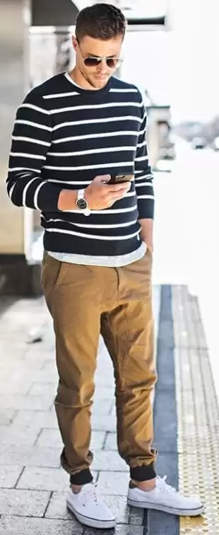 beige chino joggers with blue and white stripped full-sleeved tshirt and white sneakers accessorized with shades adn a watch