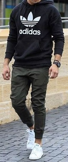 green men's joggers with black hoodie and white sneakers accessorized with a watch