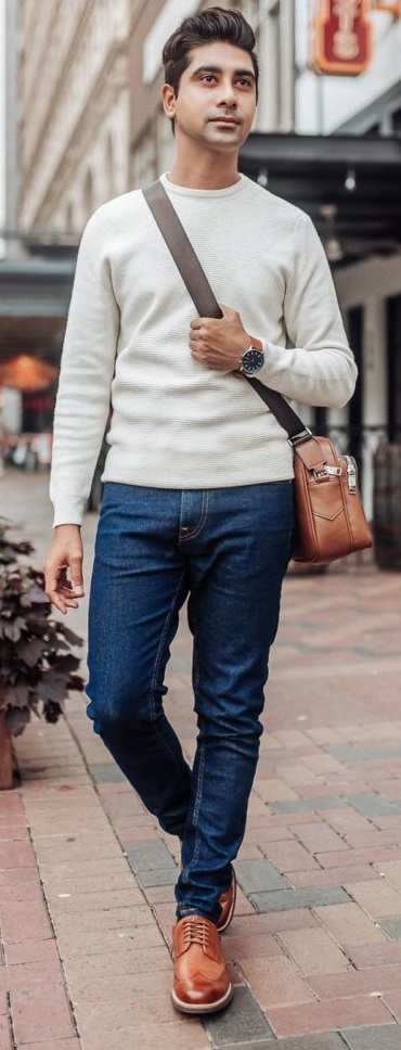 brown brogue leather shoes with a white full-sleeved tshirt and denims accessorized with a bag and a wrist watch