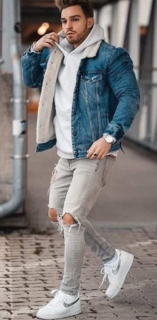 a denim jacket with grey hoodie and ripped denims, accessorized with the sneaker brand Nike and a watch