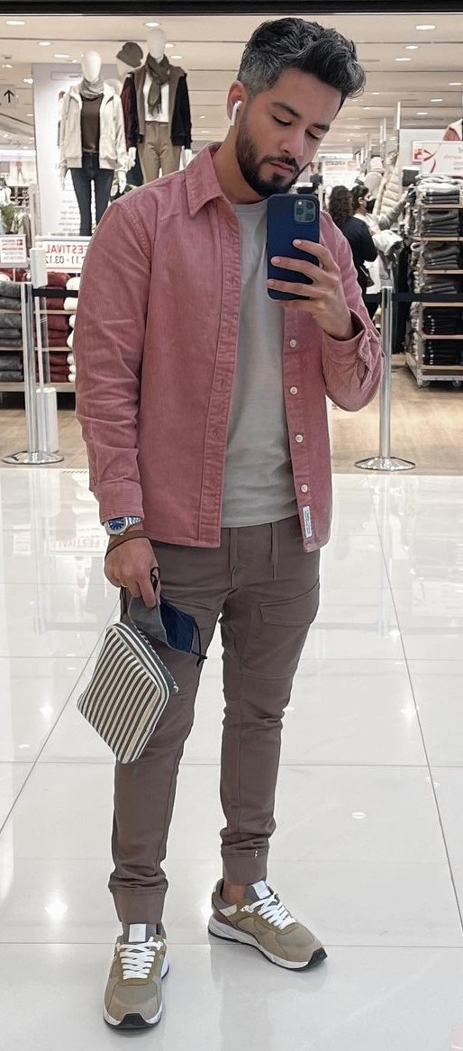 cargo pants in brown color with white tshirt and a pink jacket, accessorized with a bag, watch and air pods that completes the look with brown shoes