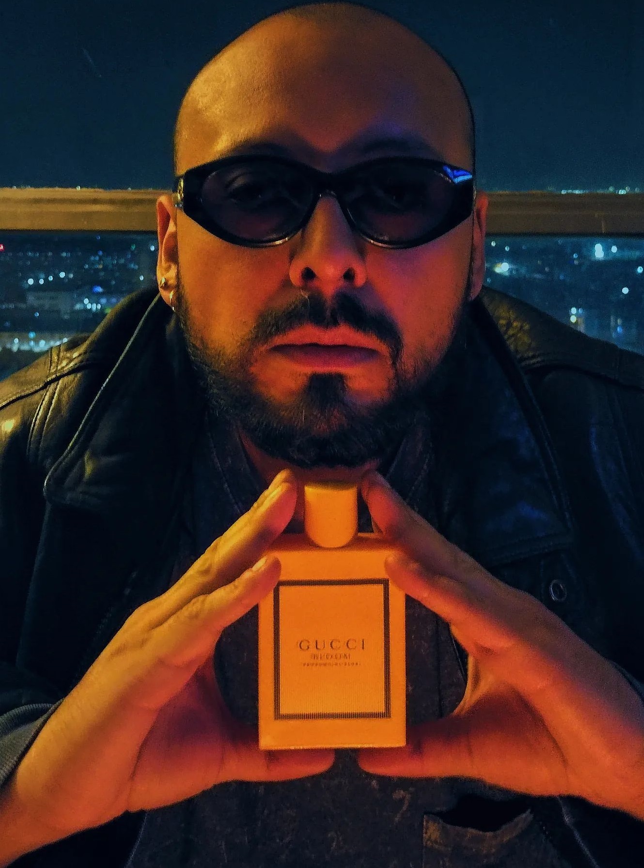 Gucci perfume being a must-have product to own, a man holding it, who is wearing shades