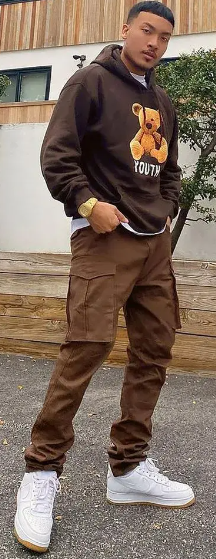 street style cargo pant in brown color with brown hooddie, accessorized with a watch and wearing a white sneaker